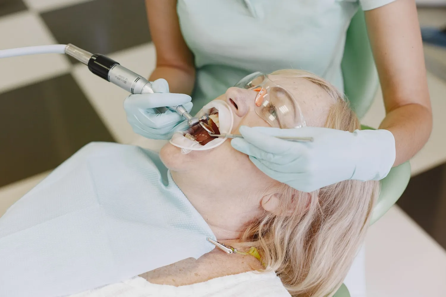 Dentist using a handpiece to polish a patient's teeth during a check-up and clean