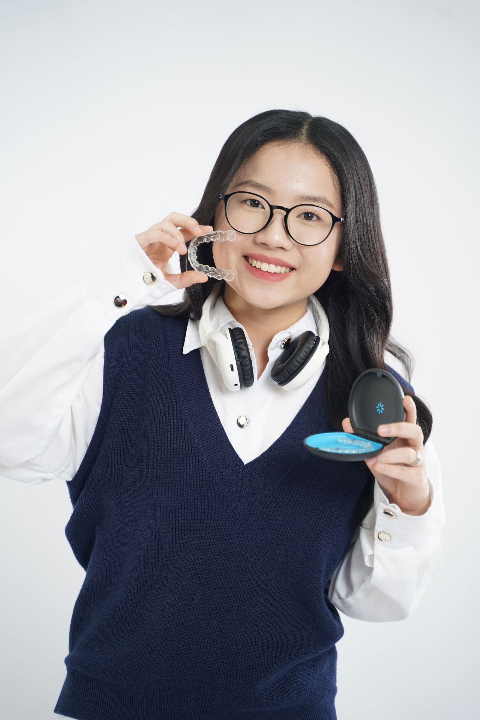 Smiling woman holding a clear aligner tray next to her mouth