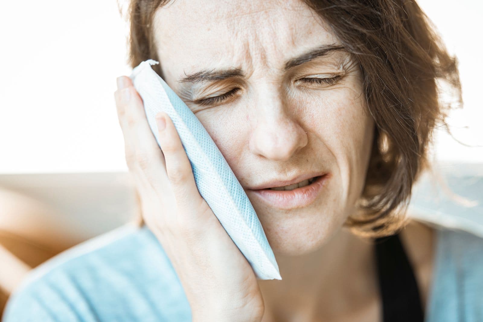 Woman holding a cold compress against her cheek to reduce dental swelling