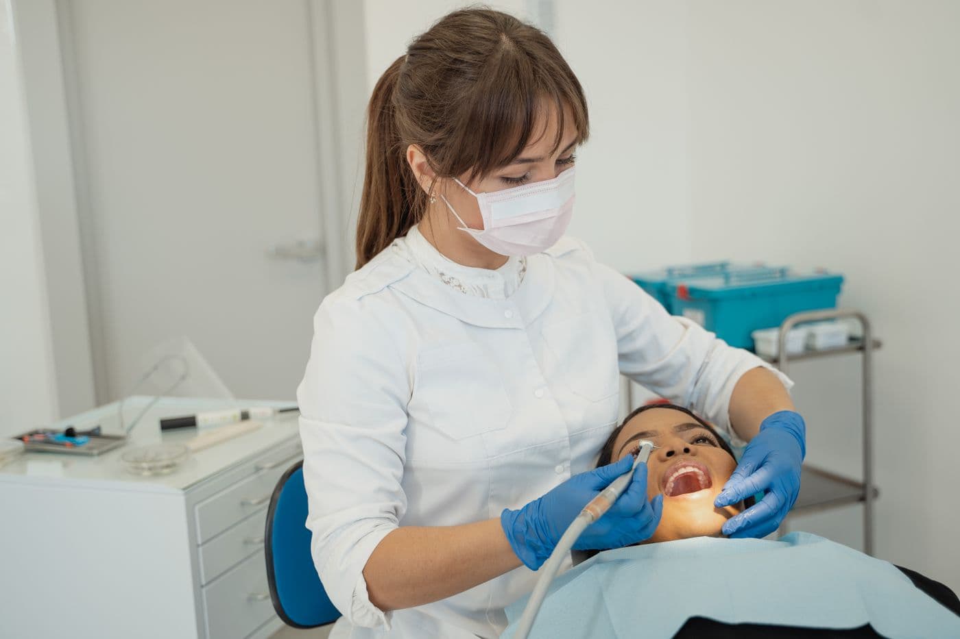 Dentist in a mask treating a patient with a dental handpiece