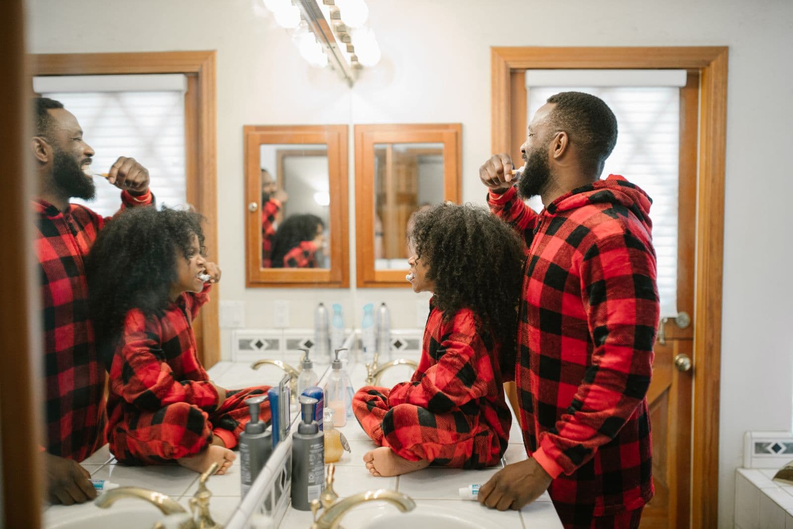 Father and daughter brushing their teeth together at the bathroom sink