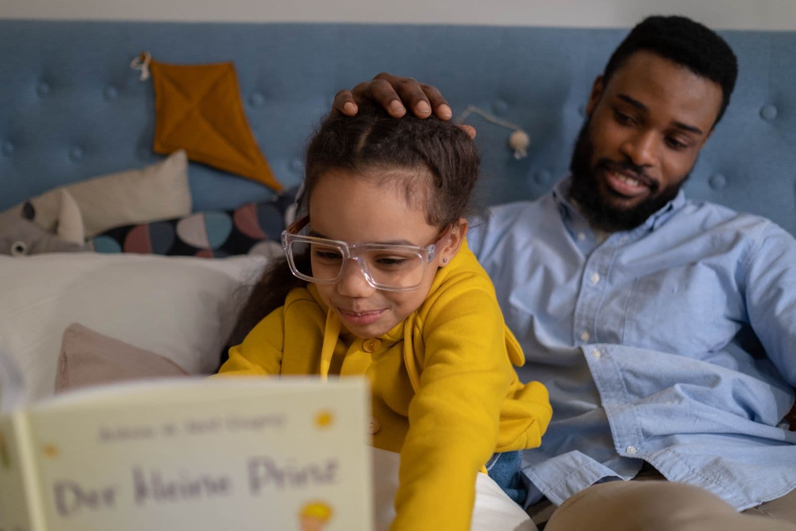 Father reading a book with his daughter at home