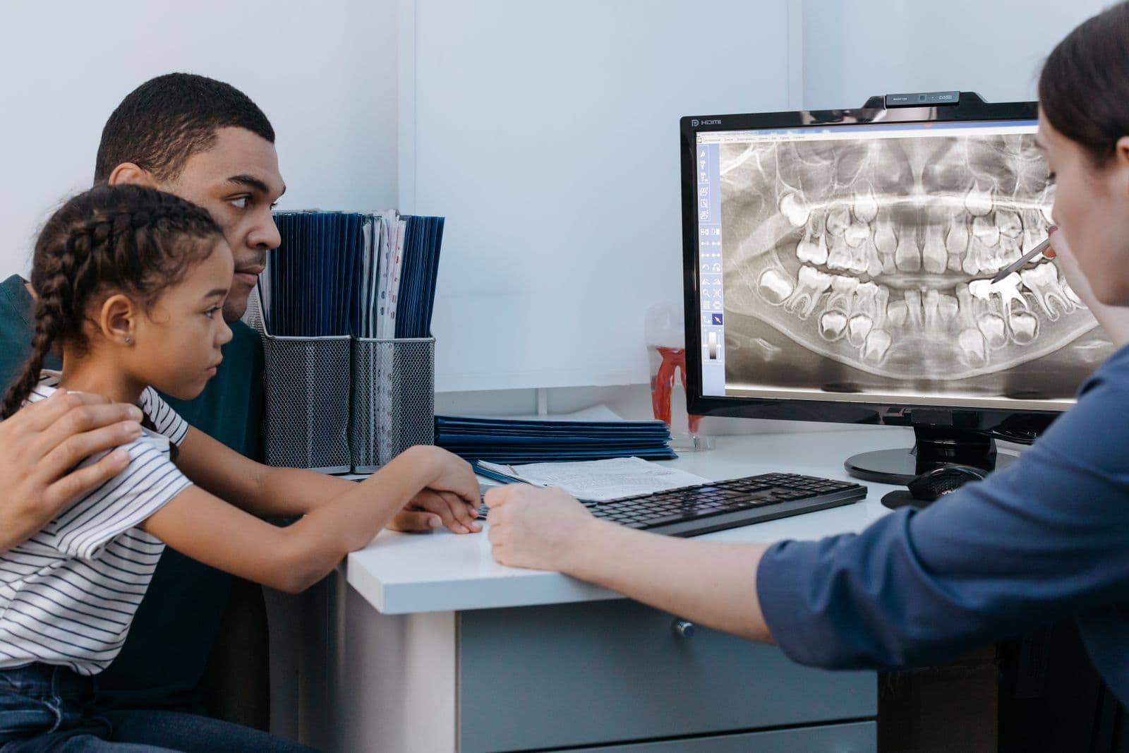 Father and daughter looking at a dental X-ray on screen with their dentist