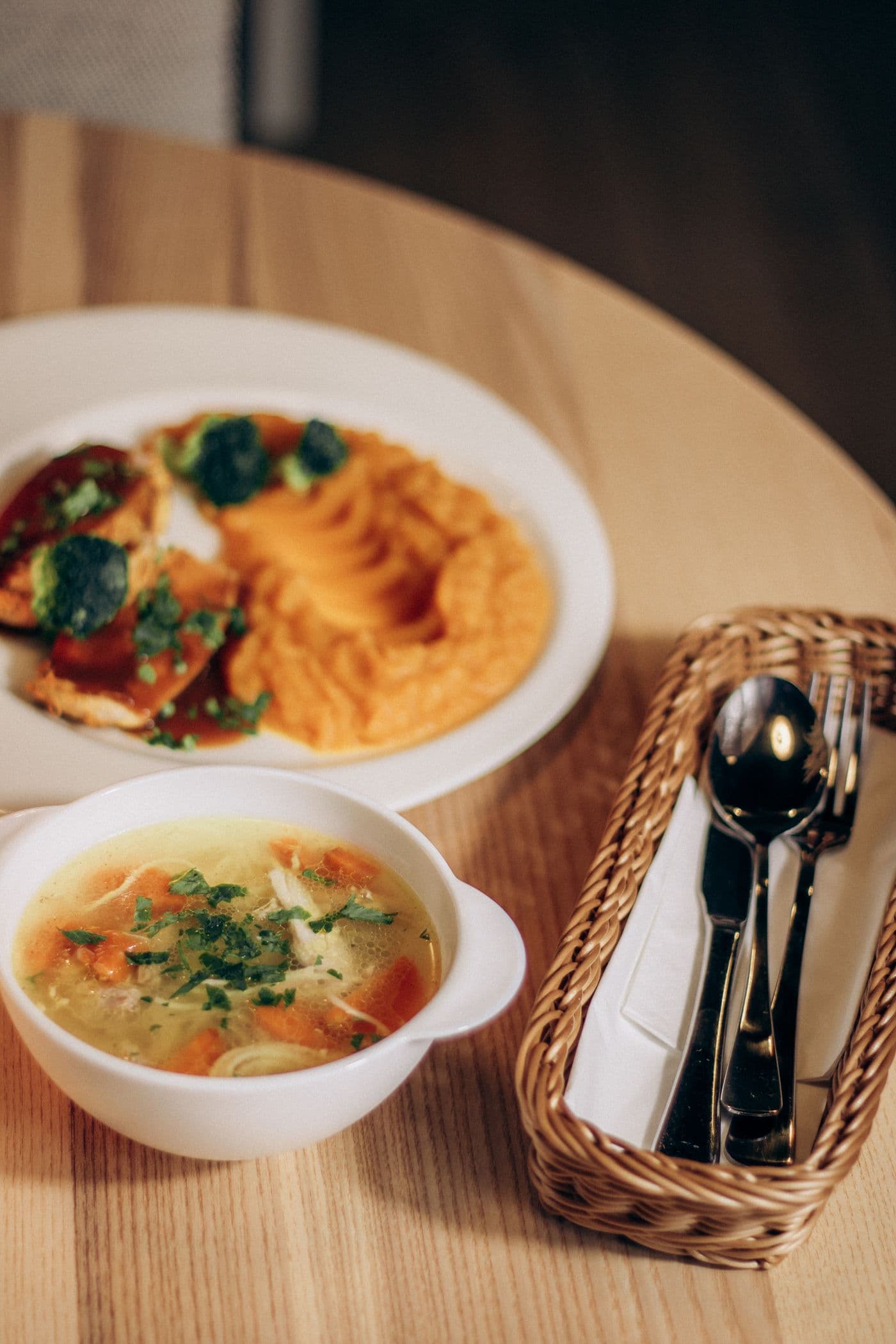Bowl of chicken soup and a plate of mashed sweet potato, soft foods for recovery