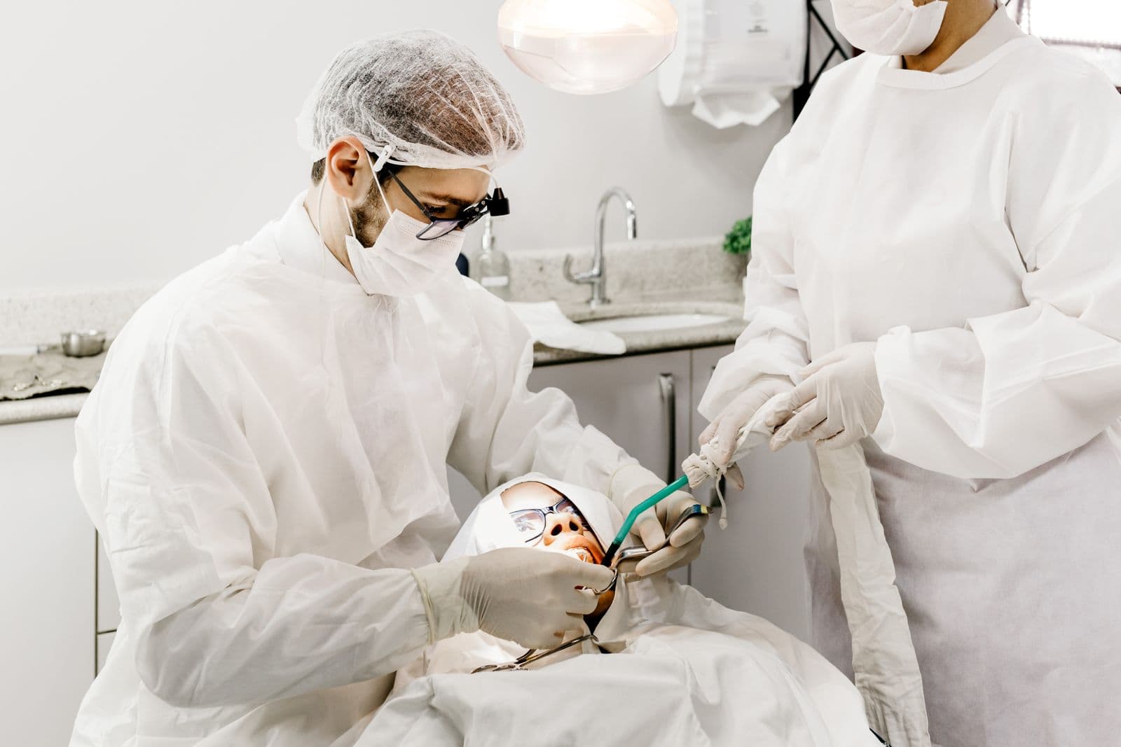 Dentist in full protective equipment treating a patient during an urgent dental appointment