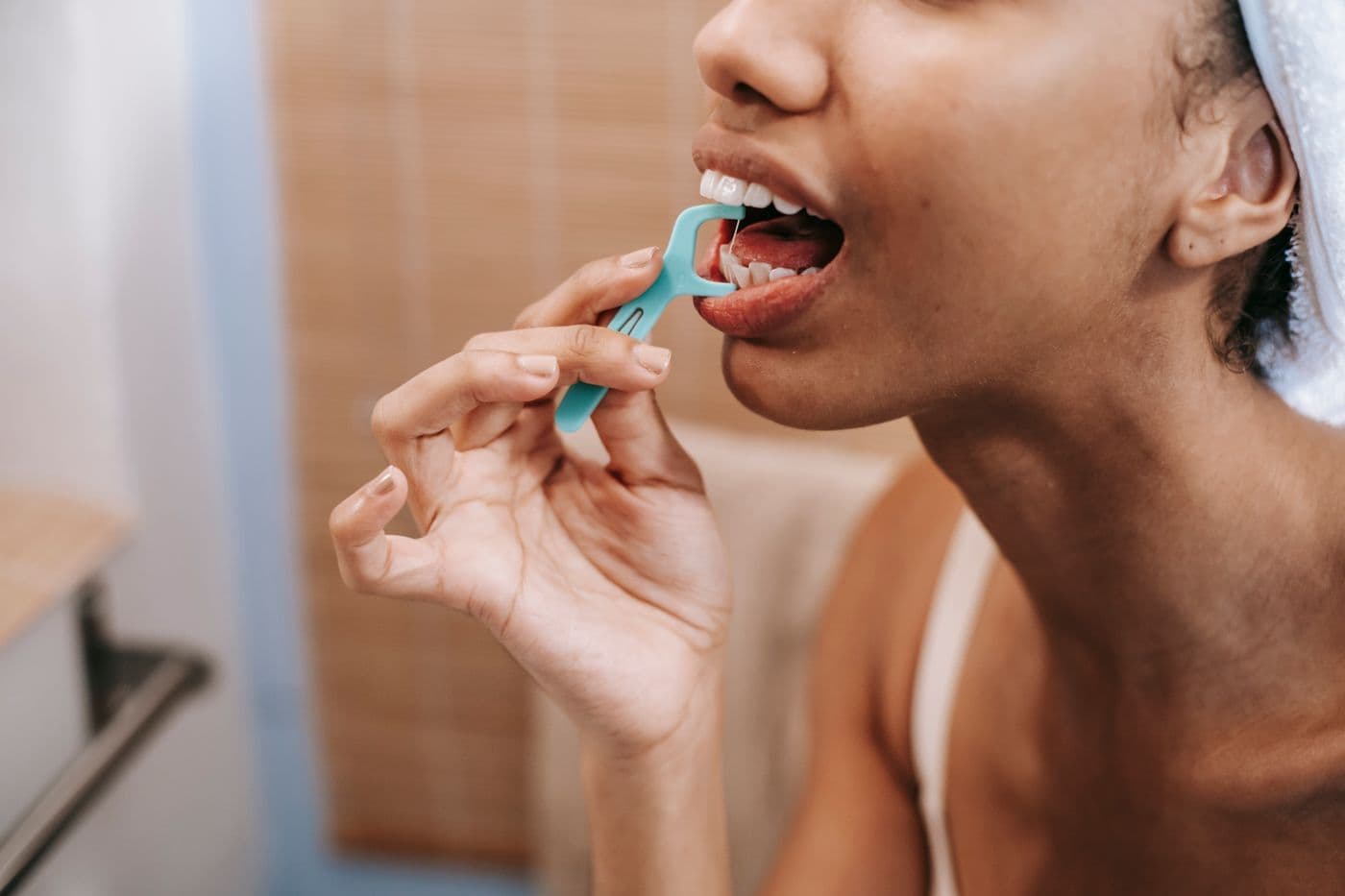 Woman cleaning between her teeth with a floss pick